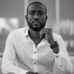 Black and white portrait of a stylish man in a white shirt indoors.